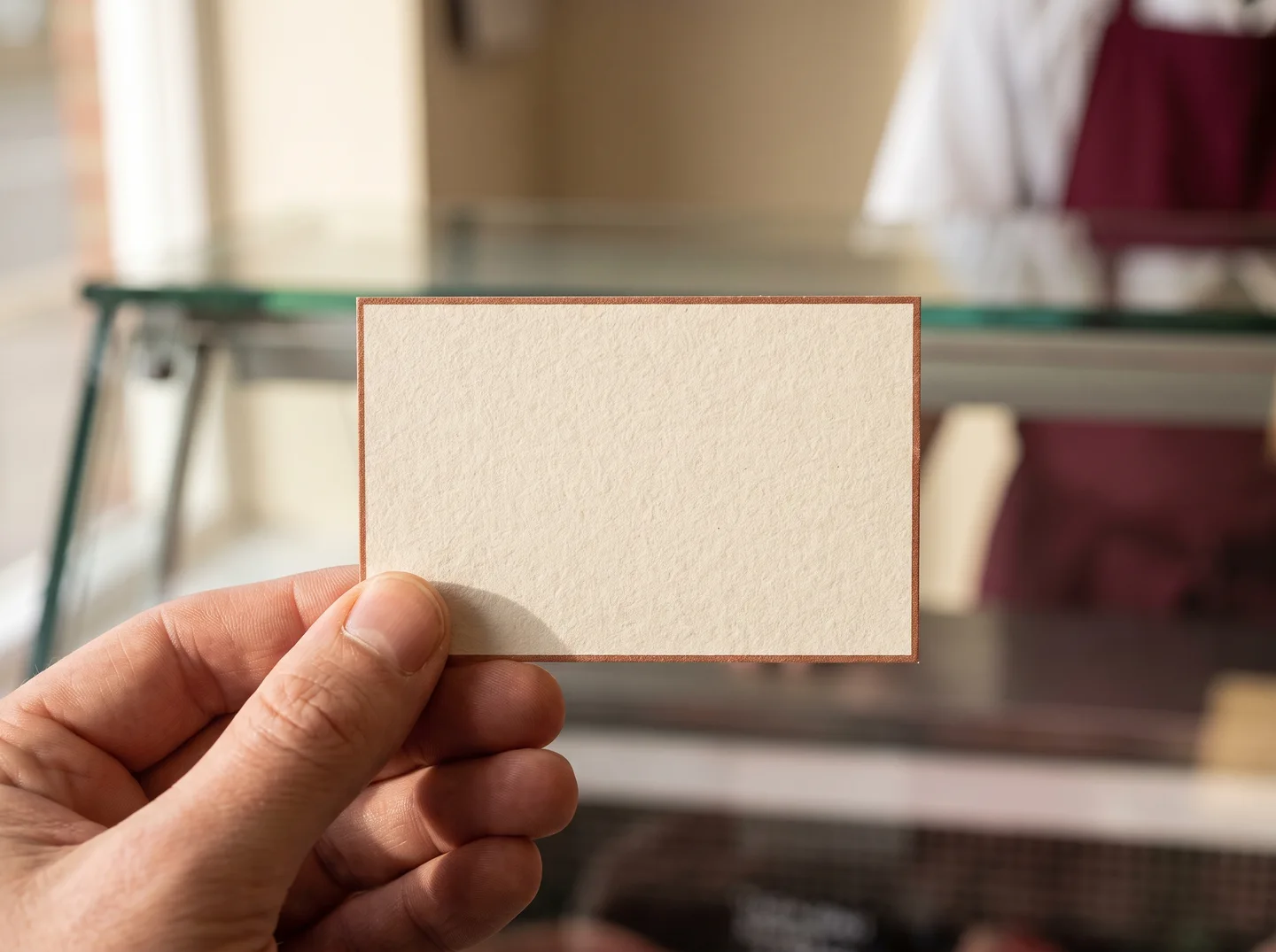 Concept photograph of a hand holding a blank cream butcher card; actual draft card PDFs are available on kit pages