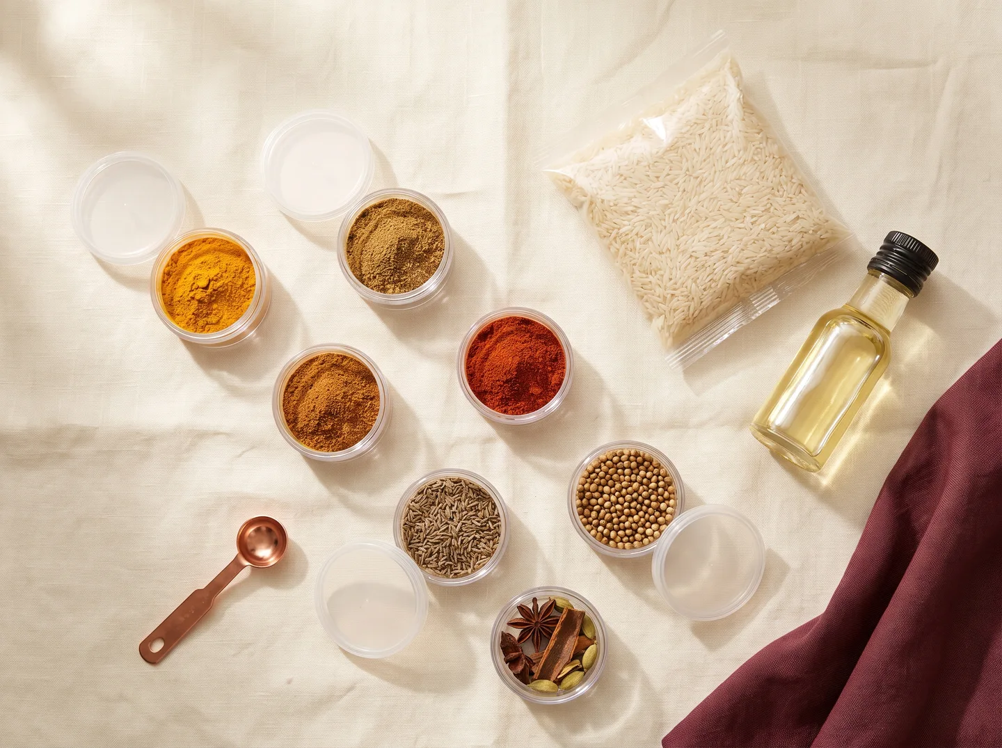 Concept photograph of pre-measured spice pots, rice and a sealed bottle of oil